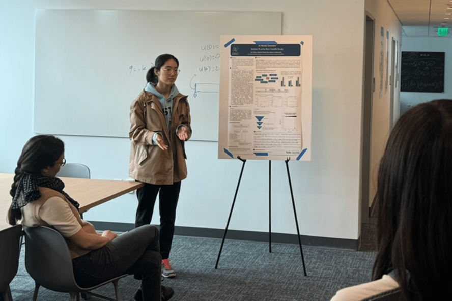 A students presents their poster to an audience at Tufts University.
